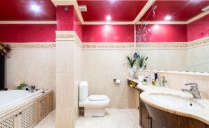 Fotografía inmobiliaria de un baño colores beige y borgoña.