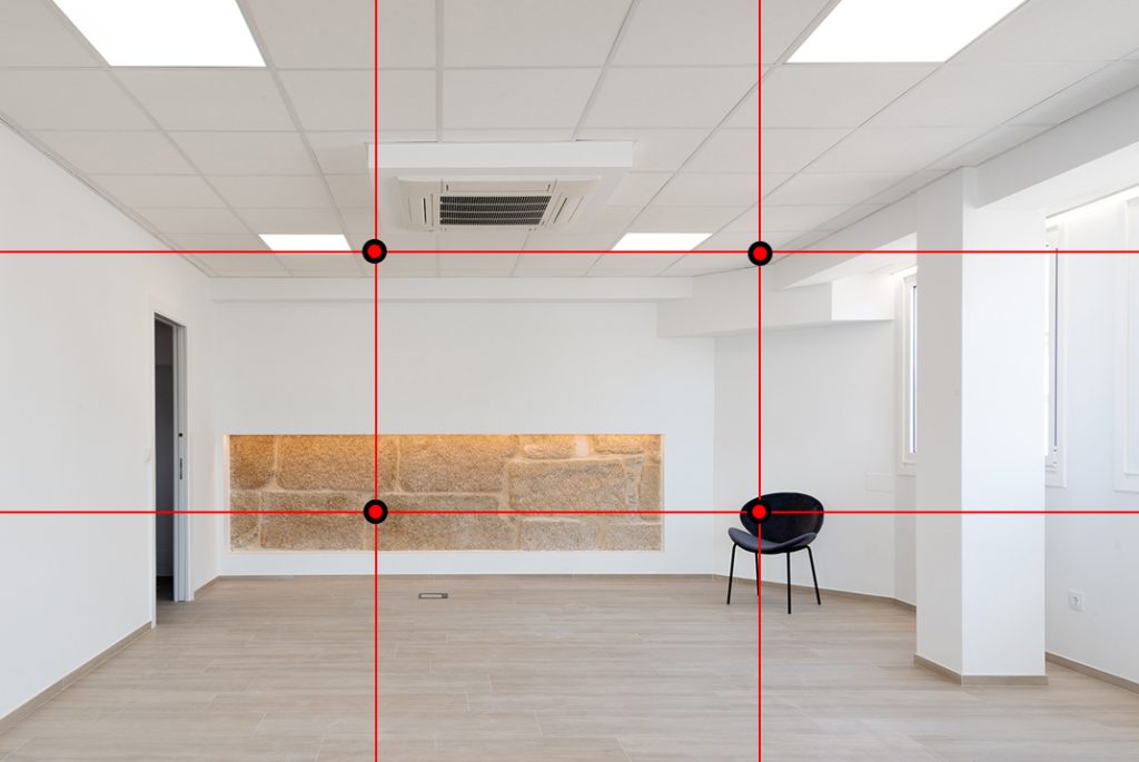 Imagen del interior de una sala para reuniones. Al fondo en la pared hay una parte revestida de piedra.
El techo y las paredes son de color blanco, el suelo es tarima flotante de color madera claro. Del lado derecho del tercio hay una silla negra.